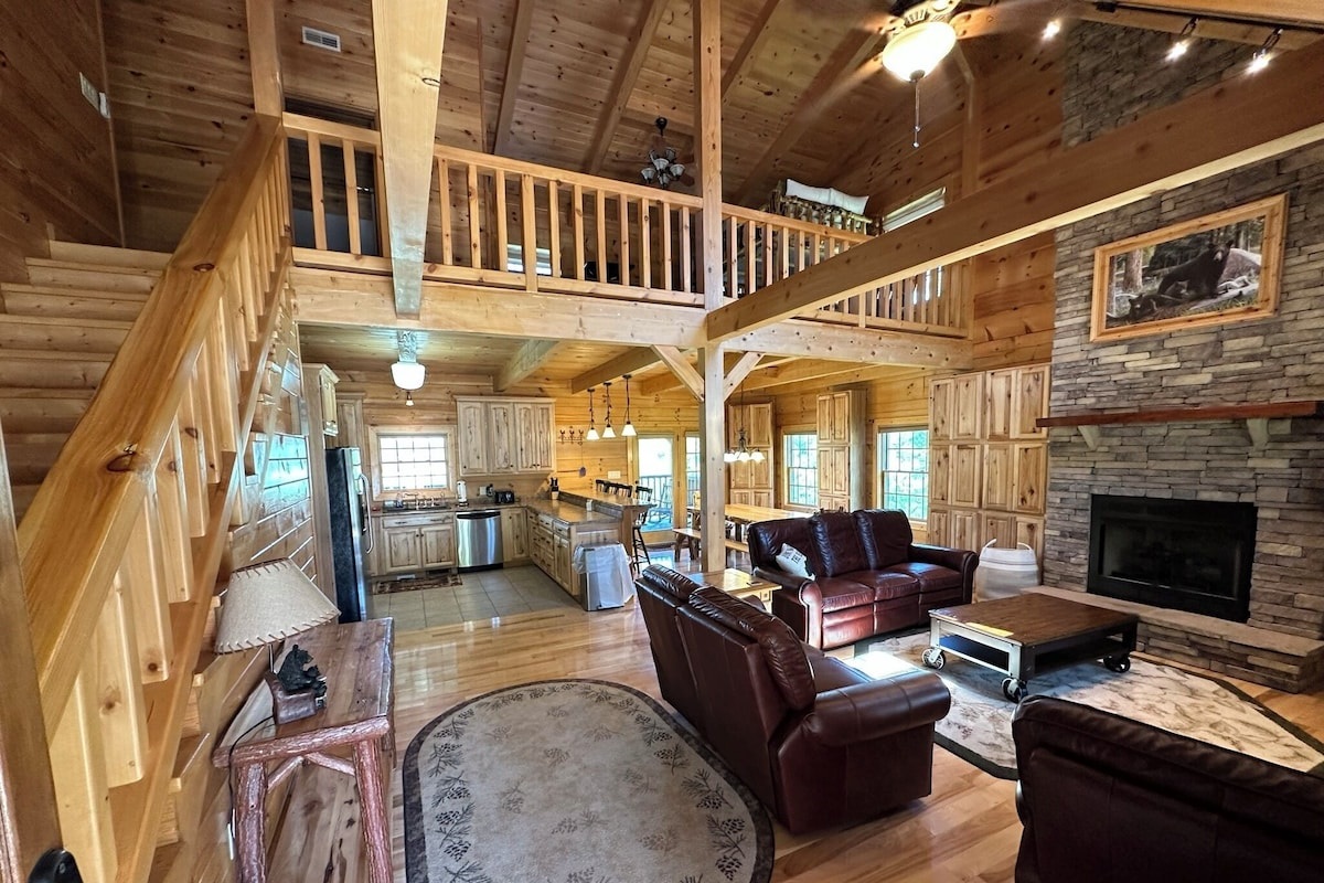 This is the view as you walk in the front door of the cabin. You will see a large open area with a view of the kitchen, the dining area, the living room, and the fireplace. 