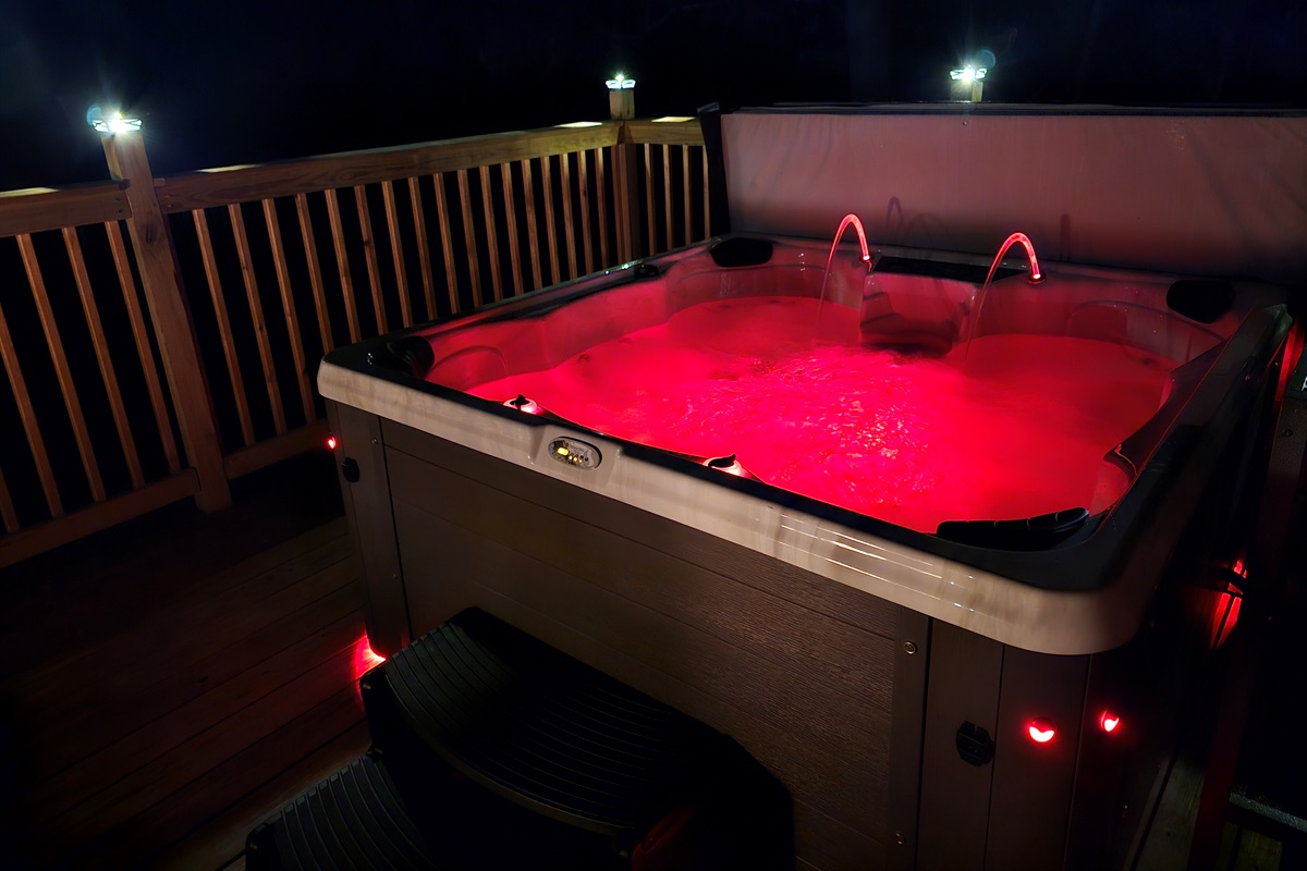 Hot tub illuminated at night with LED lighting and deck railing lights.