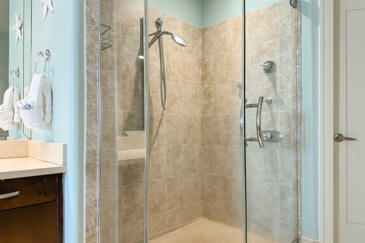 Featuring a sleek glass shower enclosure, a stylish vessel sink atop a rich wood vanity, and a large mirror amplifying the space, this bathroom blends functionality with modern aesthetics.