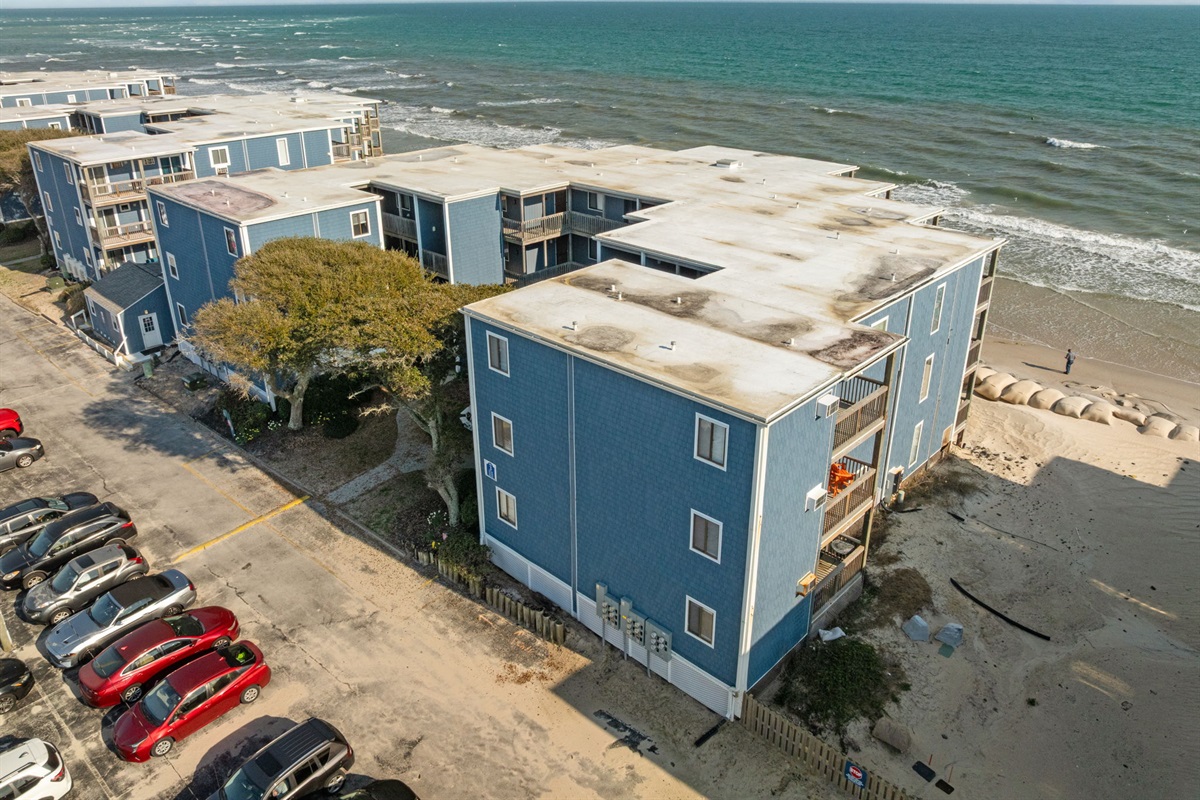 Angled aerial showing the oceanfront location and nearby parking area