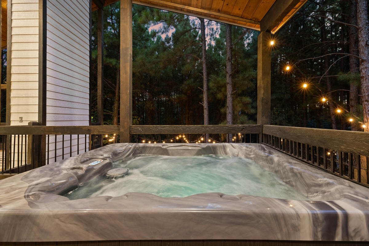 One last soak before bed. Slip into the hot tub beneath the covered deck while the string lights glow through the trees around you.