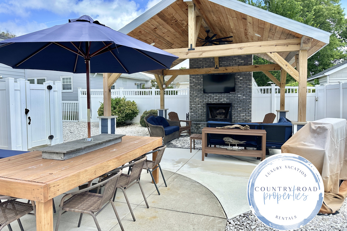 Savor alfresco meals at the spacious wooden dining table in your private backyard. This inviting space connects to a luxury covered lounge with a stone fireplace and TV, creating the ultimate setting for vacation entertaining.