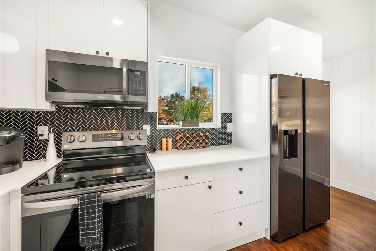 Fully stocked kitchen with stainless appliances cookware, spices and serving ware.