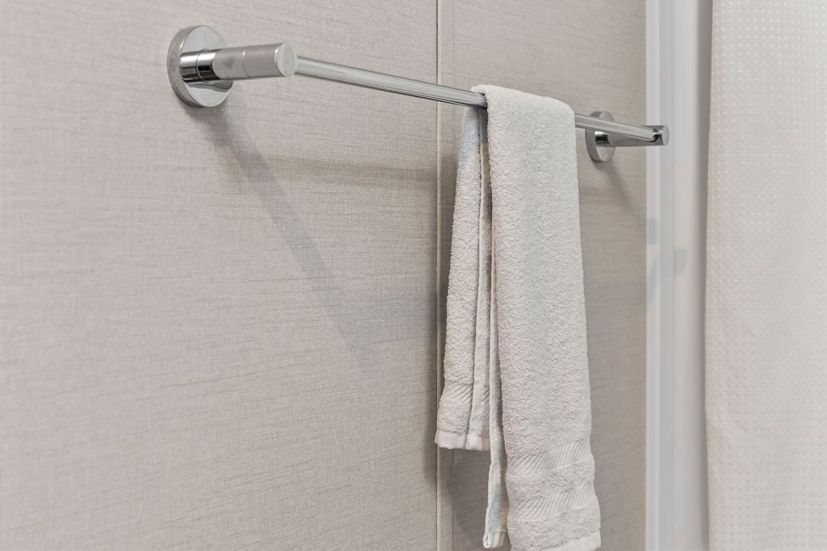 Fresh towels neatly arranged on a sleek towel bar, adding a clean and hotel-style touch.