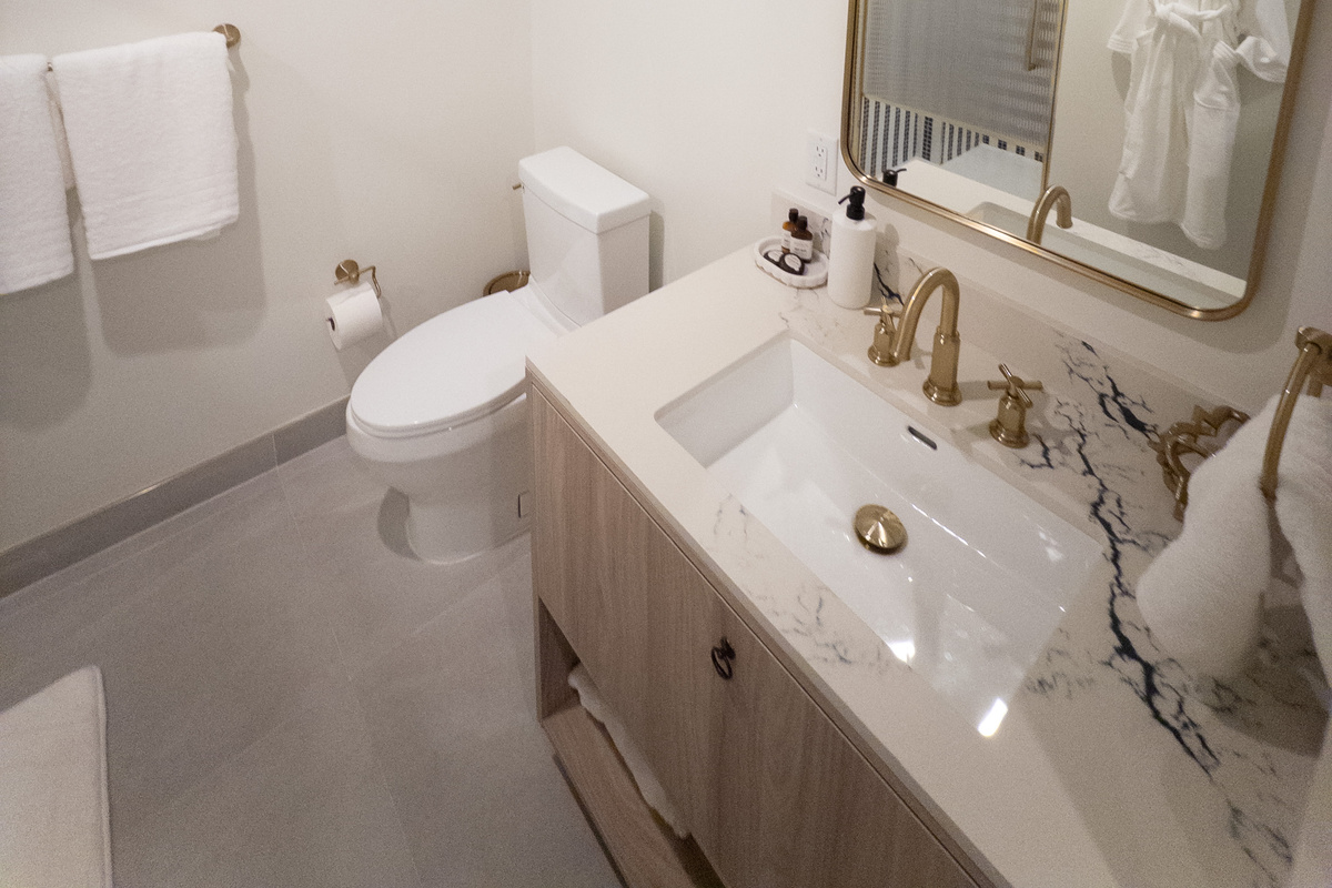 Sleek full bathroom - floating wood vanity, walk-in glass shower and designer fixtures.