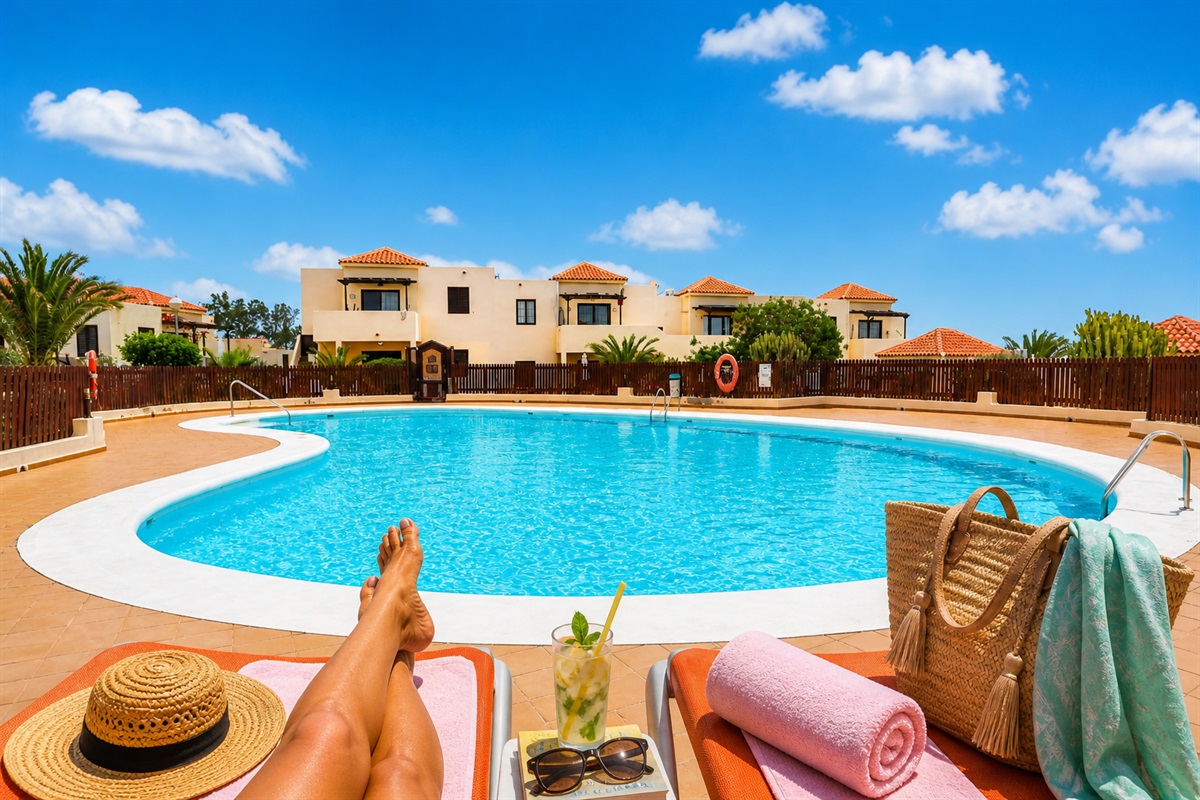 Large communal swimming pool surrounded by open spaces, ideal for enjoying the sun and cooling off during your stay.