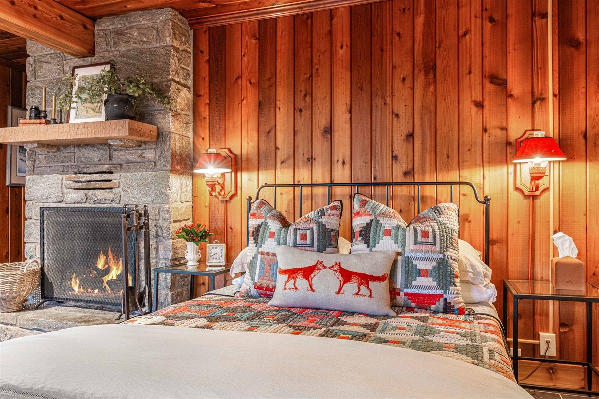 Another view of the primary bedroom highlights the inviting fireplace and warm wood tones, creating a peaceful space to unwind after a day of exploring.