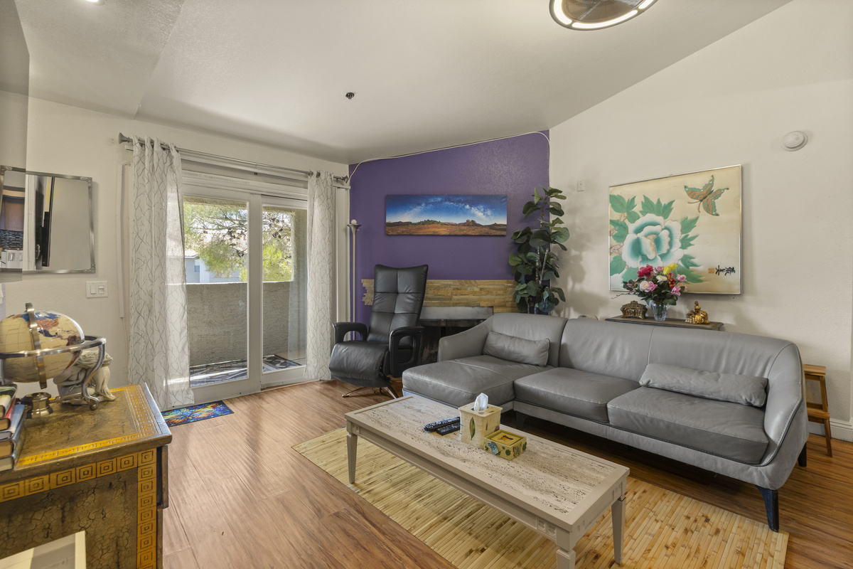 Living room with Smart TV, gray sofa seating, a recliner, balcony access, and a purple accent wall for a warmer lounge feel.