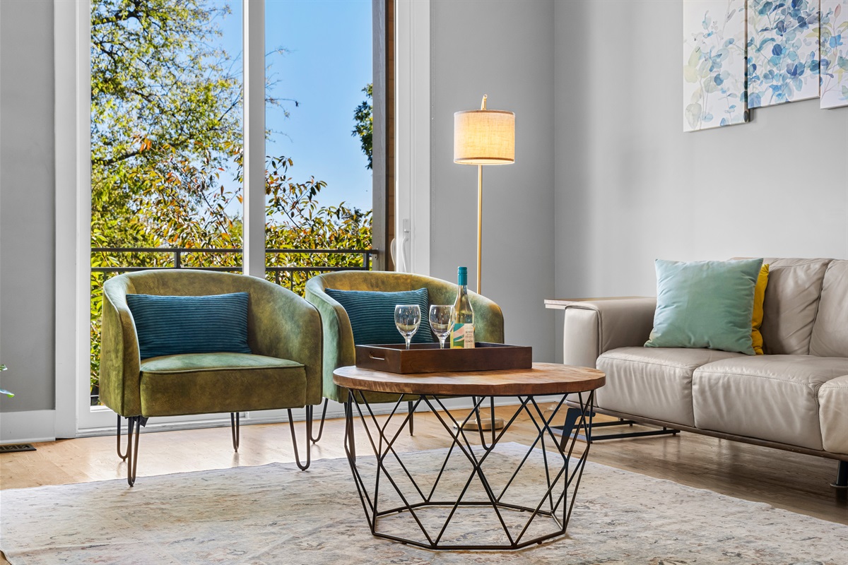 Bright, stylish living room with comfy seating and peaceful tree views.