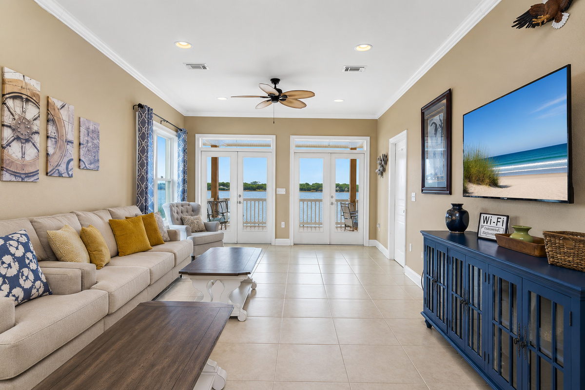 Comfortable living room with large sectional, smart TV, and French doors to the water-view balcony