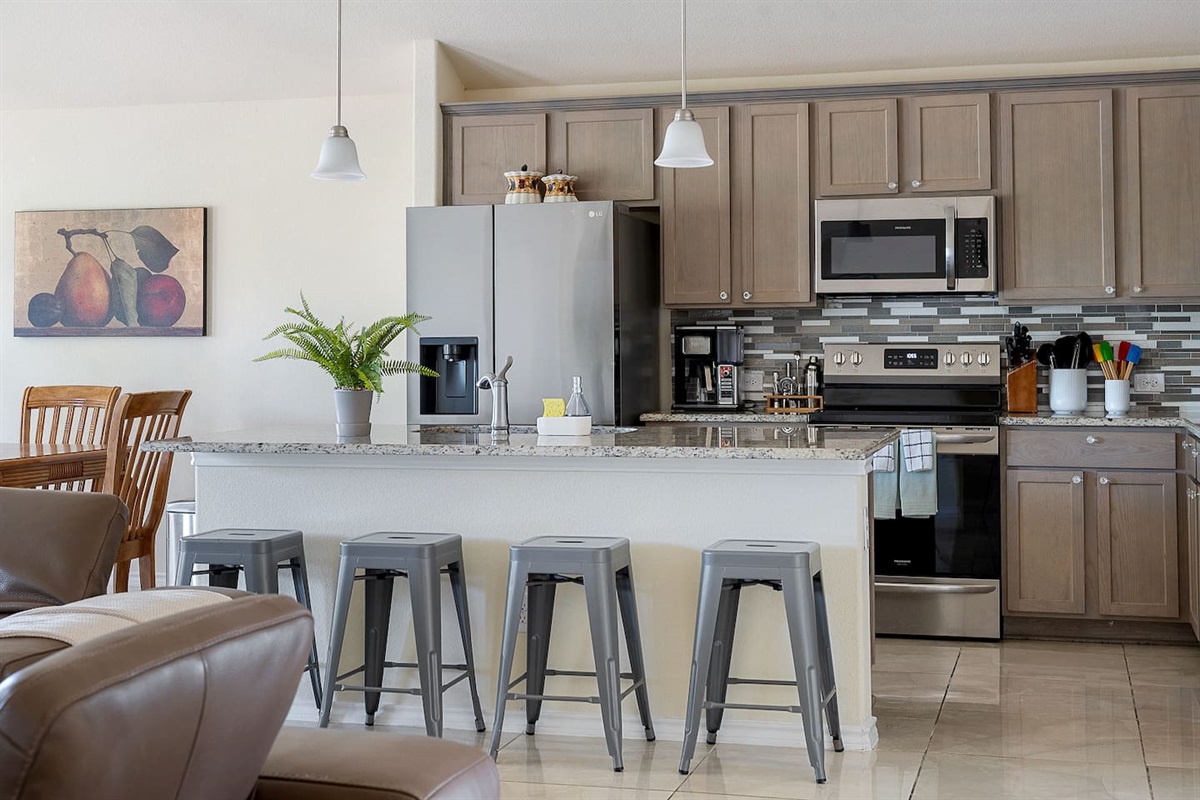 Welcome to a modern kitchen featuring stainless steel appliances, sleek cabinetry, and a spacious island with barstool seating for casual meals.