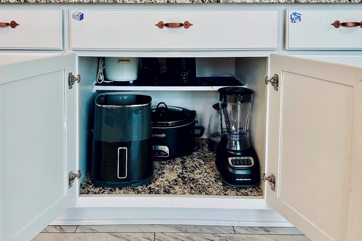 Dedicated kitchen cabinet stocked with small appliances, including an air fryer, large crock pot, small crock pot, hand mixer, toaster, electric kettle, and blender. Fully equipped for everyday cooking and extended stays.
