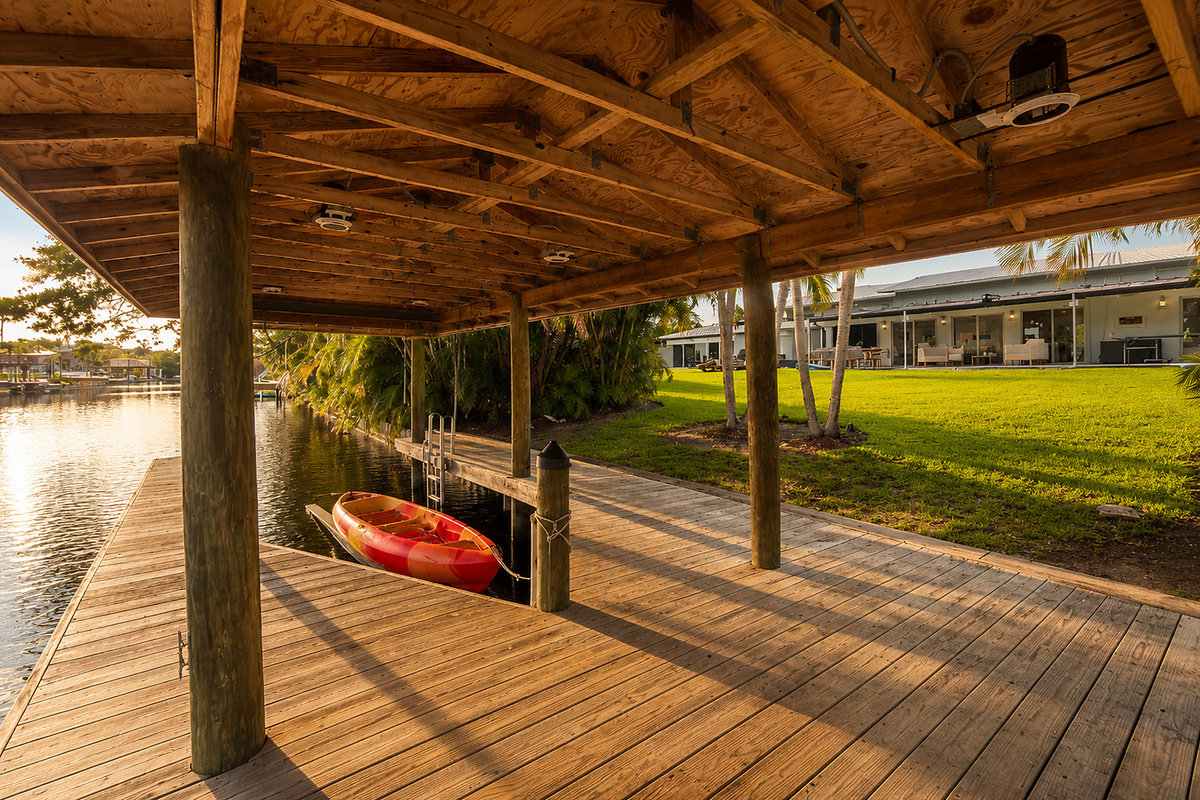 The covered dock and kayak storage add a waterfront feel to your stay, with the canal just beyond the backyard.