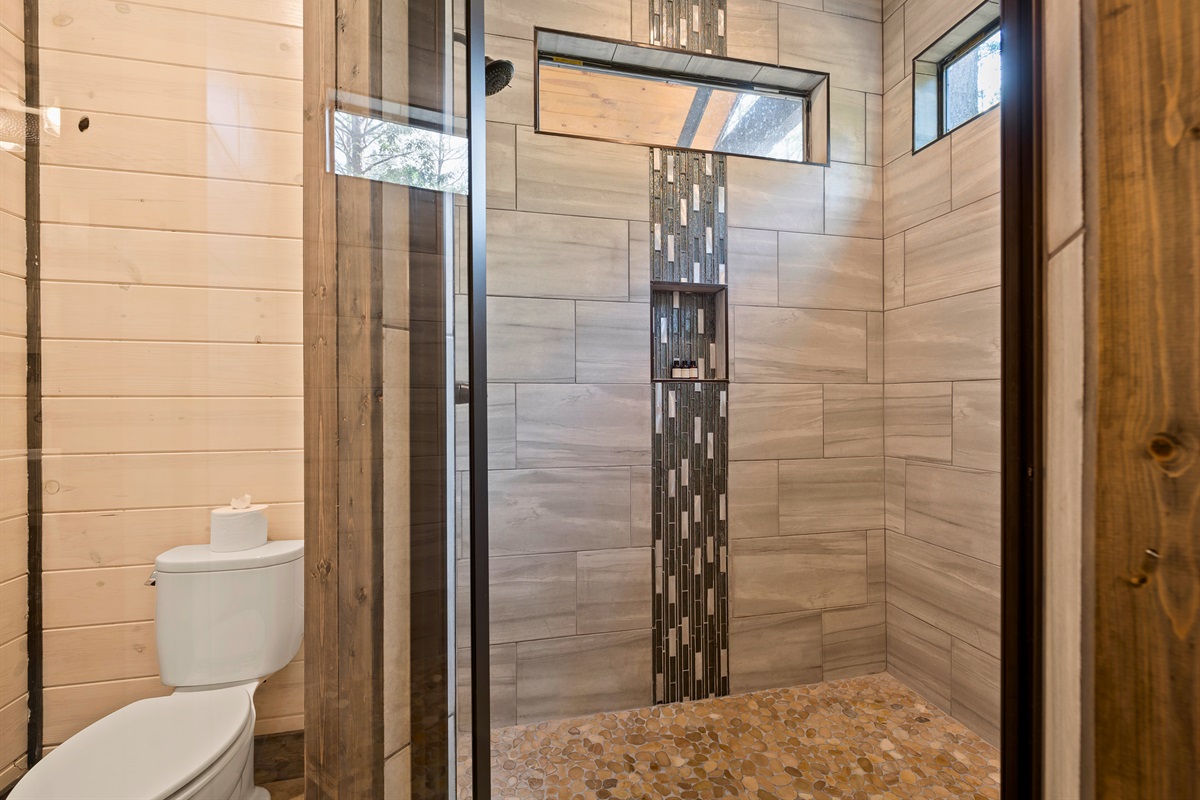 A glass-enclosed shower with detailed tiling