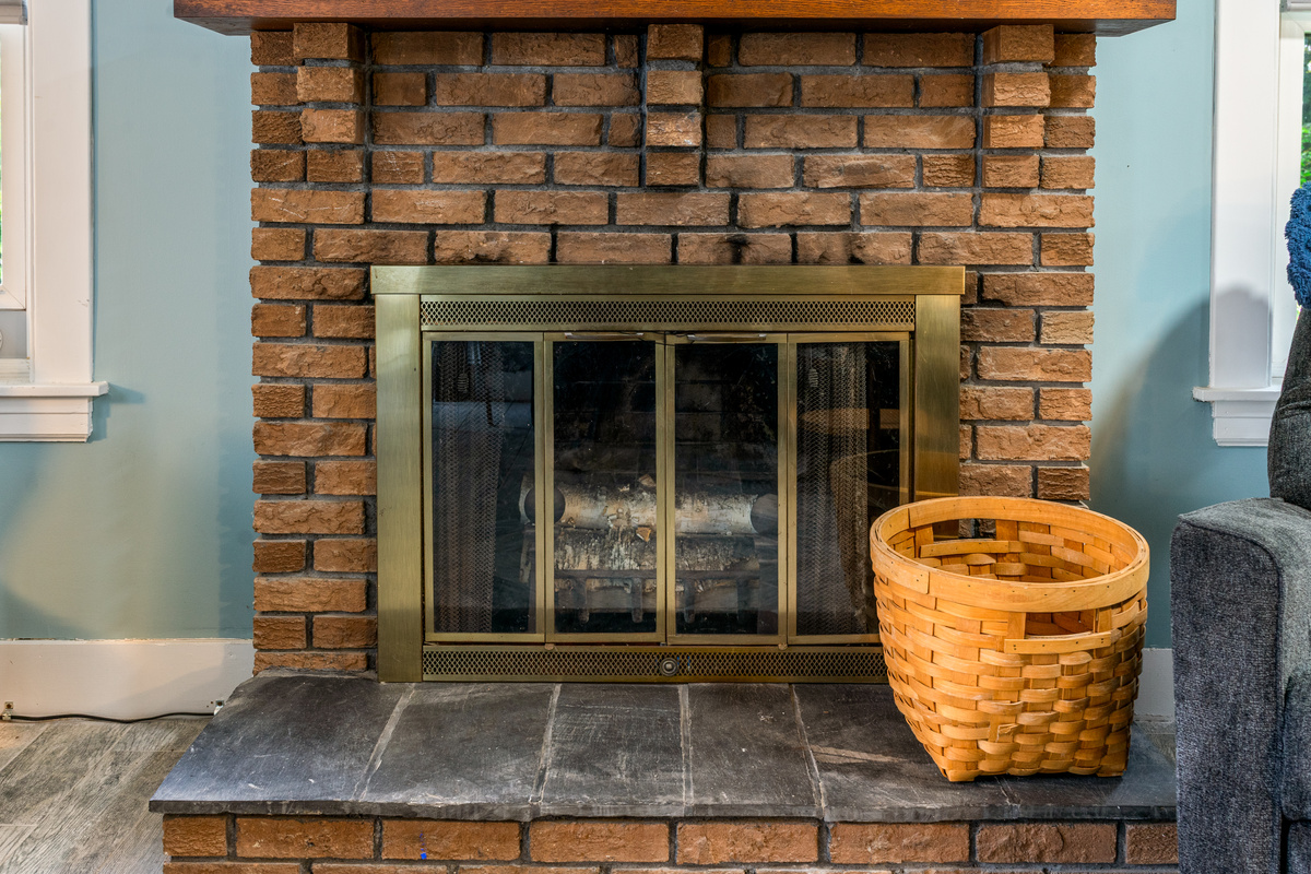 This closer perspective highlights the decorative fireplace glass doors and rustic stone layout. Acting as a beautiful focal point, this non-functional brick hearth adds a warm touch of traditional Maine charm to your group's main gathering space.