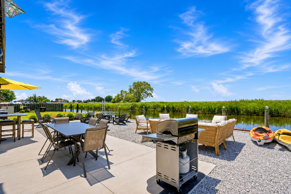 Relax by the water with a spacious patio featuring outdoor dining, a BBQ grill, cozy lounge seating, a fire pit, and complimentary kayaks for fun on the canal.