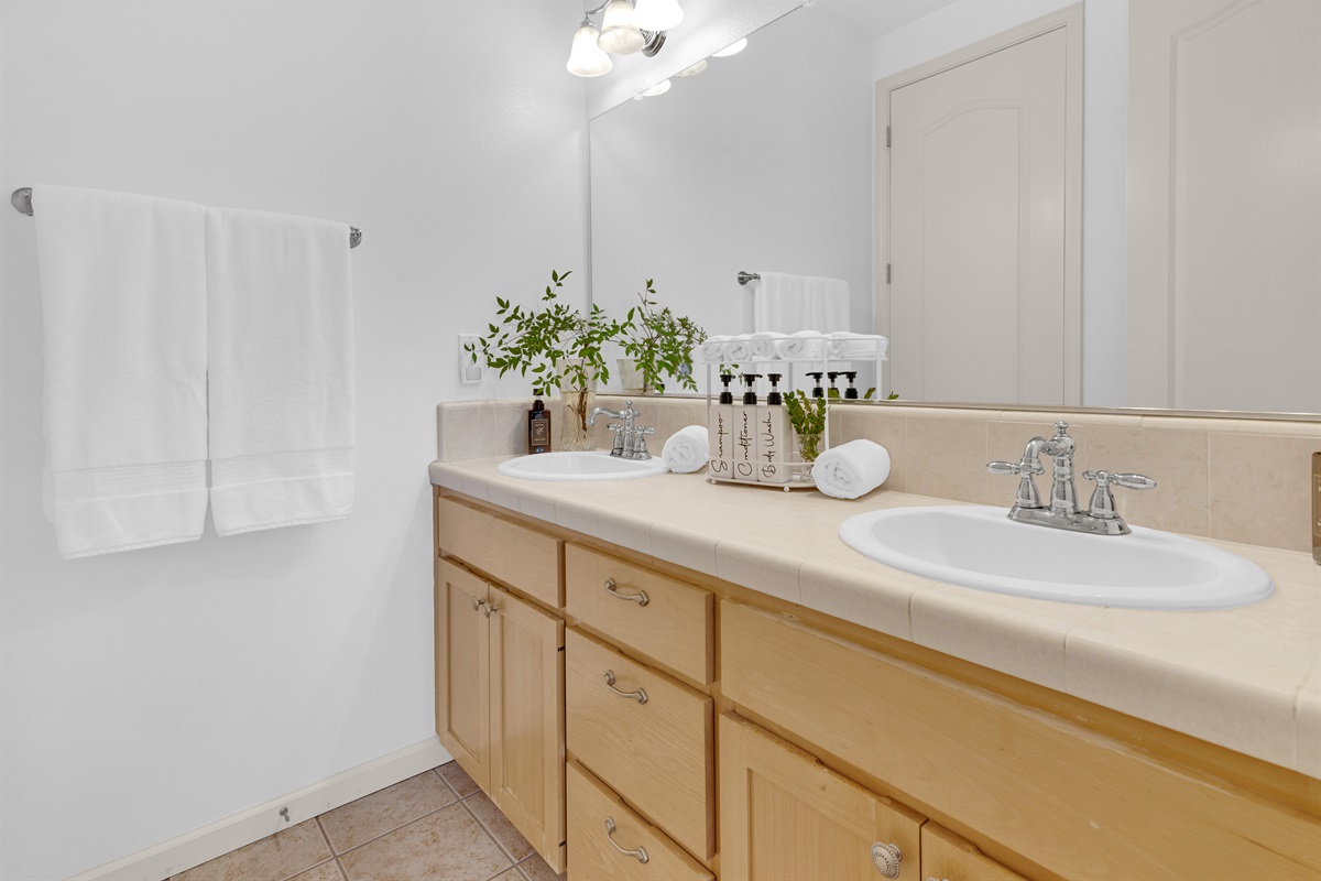 Full bathroom includes a tub and shower as well as two double sinks. Plenty of crisp white towels are provided and thoughtfully stocked with high-quality shampoo, conditioner, body wash, and hand soap for your comfort.