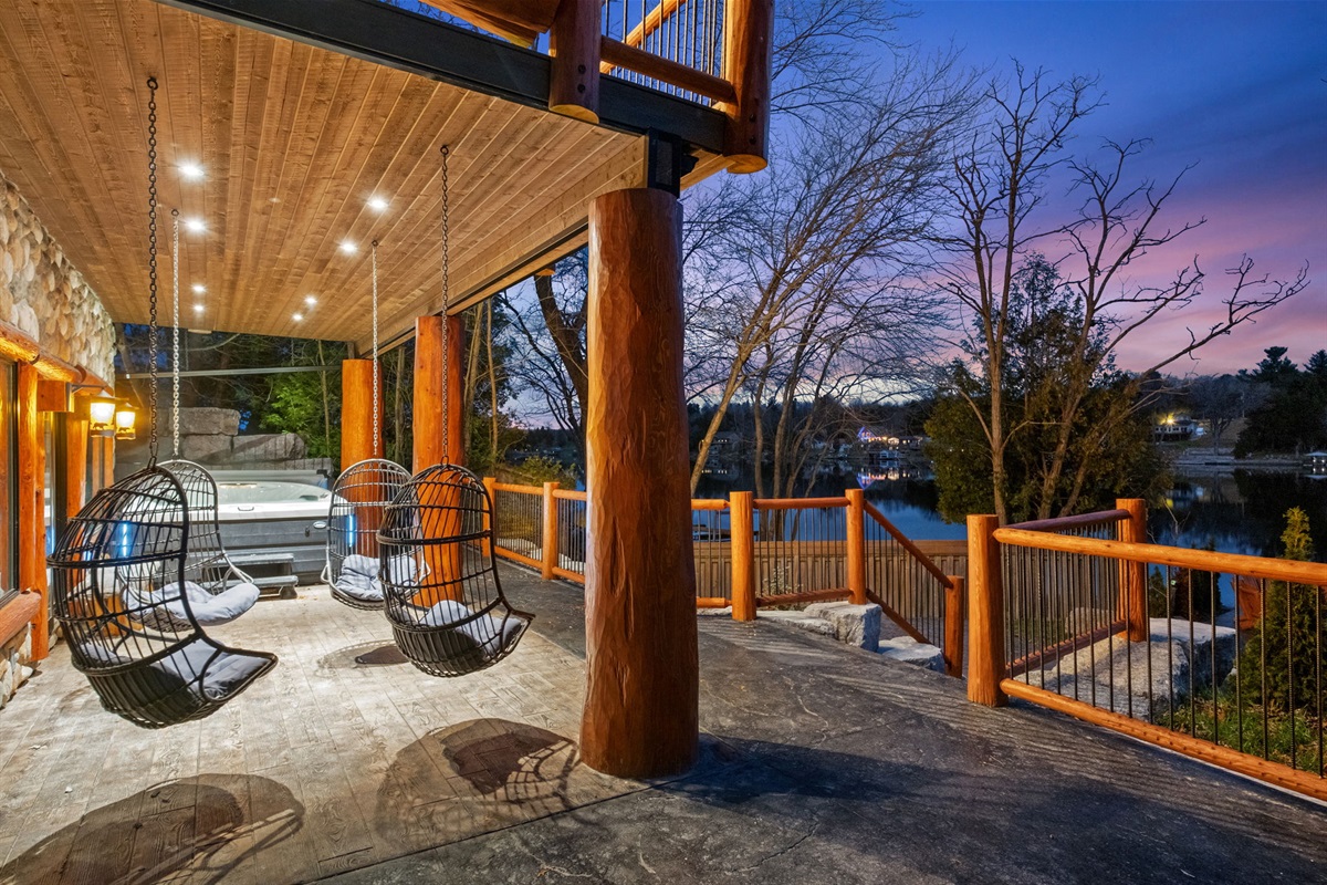 Cozy lakeside relaxation zone featuring hanging egg chairs, ambient lighting, and panoramic water views.