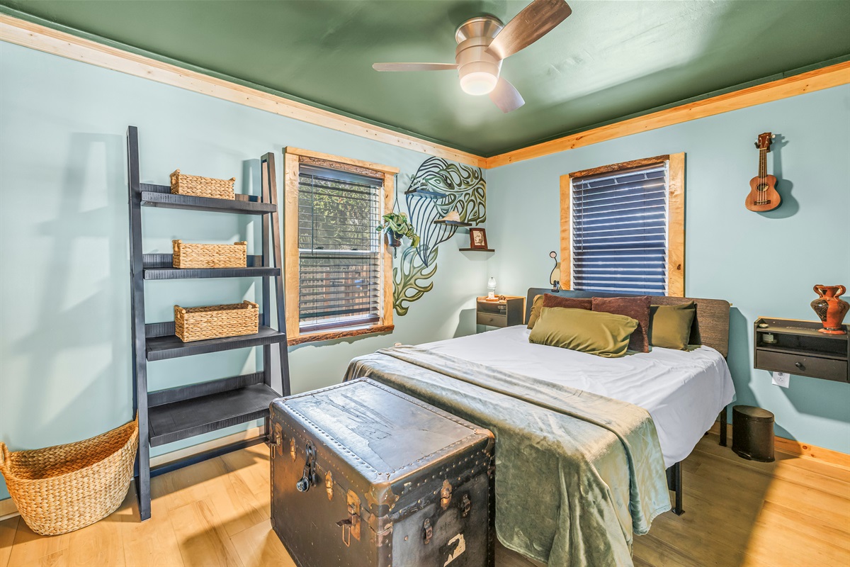 Cozy bedroom with warm wood trim, calming green accents, natural light, and thoughtful details for a comfortable stay.