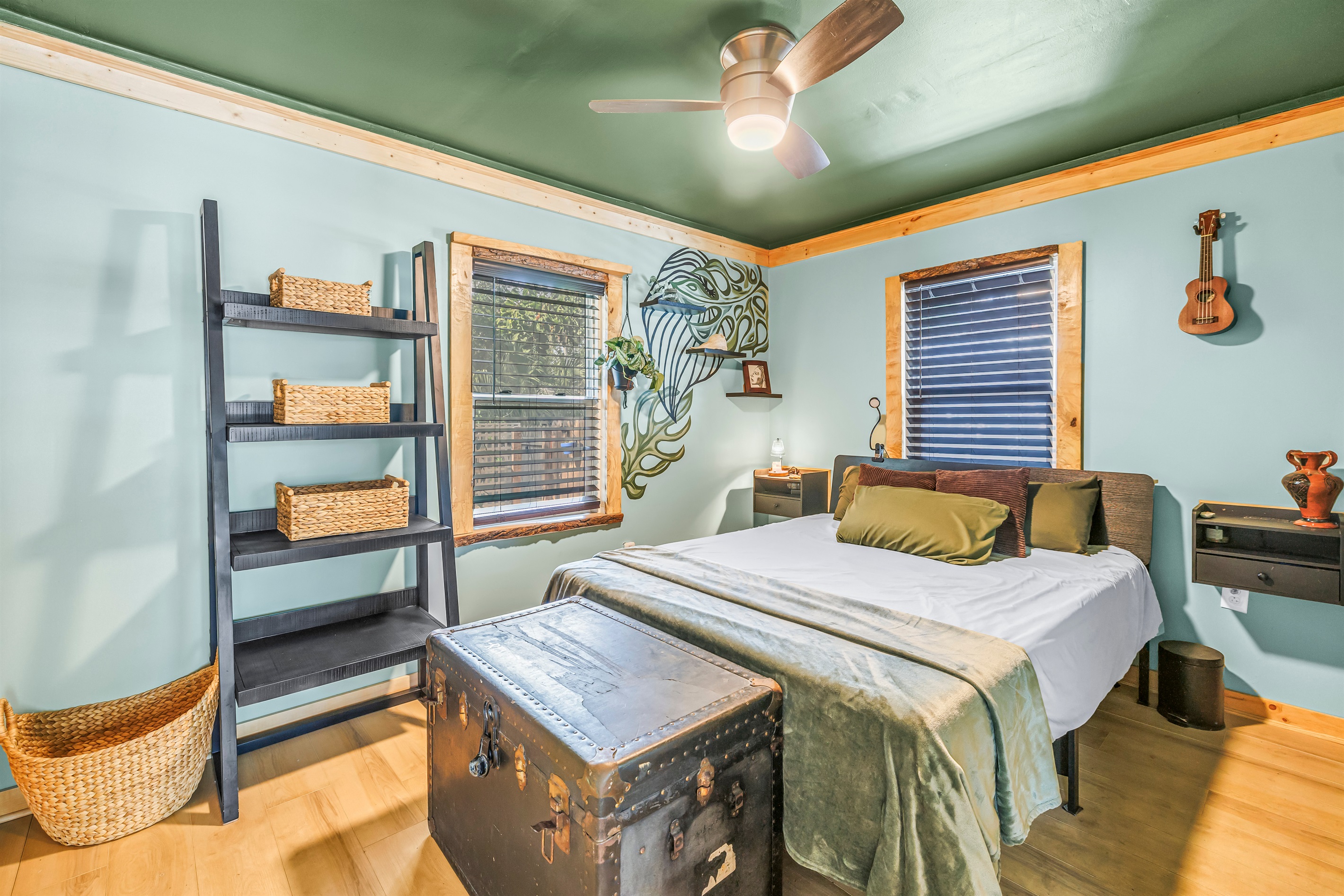 Cozy bedroom with warm wood trim, calming green accents, natural light, and thoughtful details for a comfortable stay.