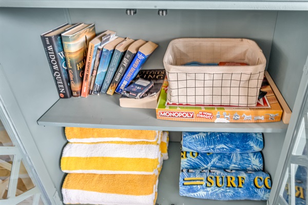 Extras shelf stocked with books, board games, and beach towels for your convenience