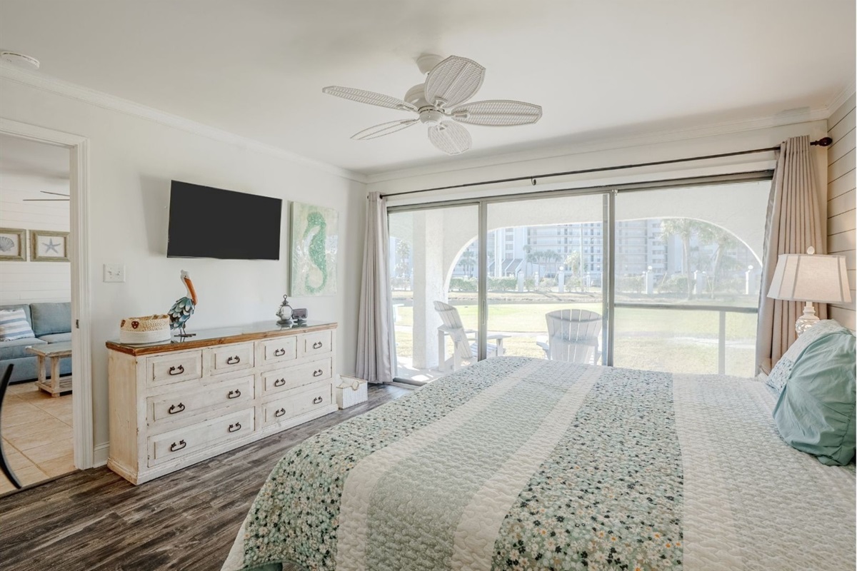 Master bedroom with king bed, patio access, clothing storage, smart TV, and ceiling fan
