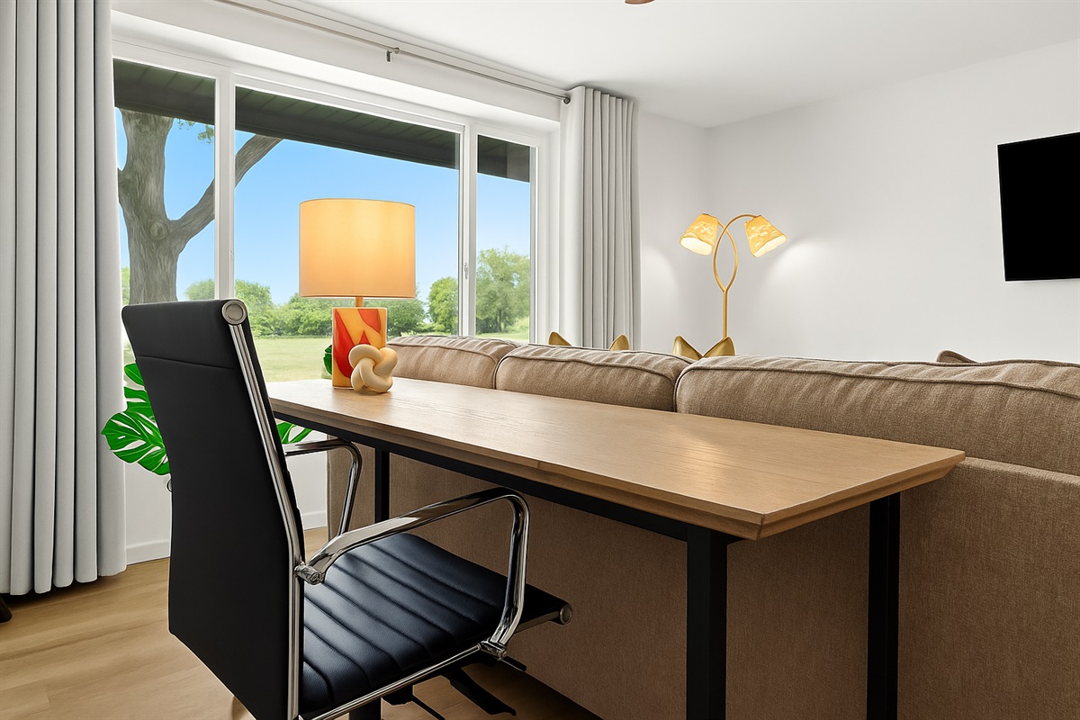 Work meets comfort with this spacious desk setup, complemented by a bright window view and artistic lighting.
