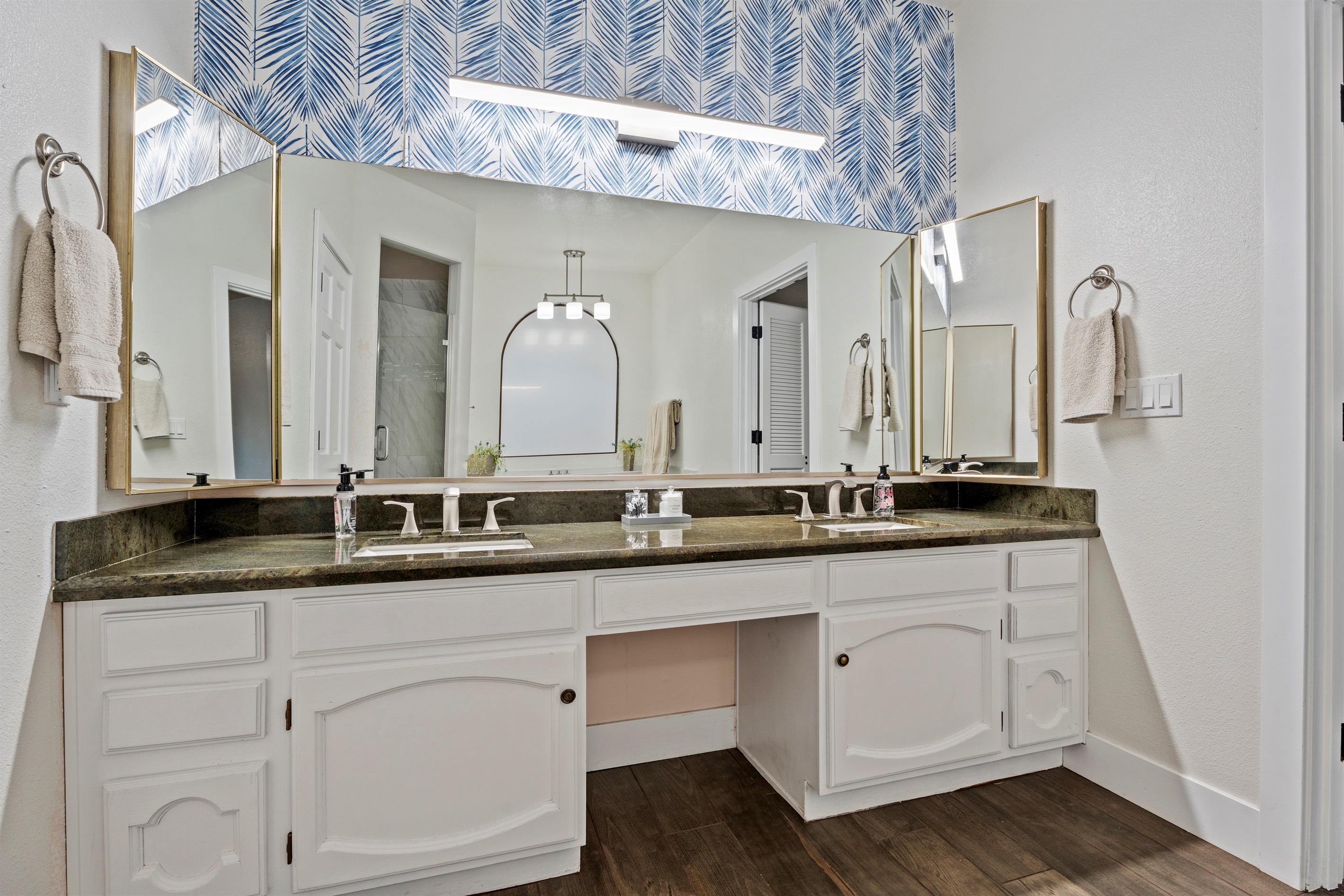 This luxurious bathroom offers double vanities, statement wallpaper, and a freestanding soaking tub made for long, peaceful escapes.