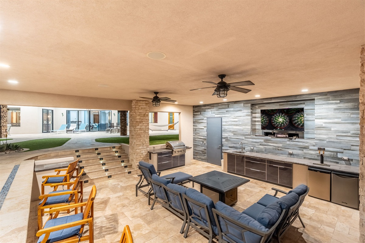 Covered backyard entertainment zone with outdoor TV and lounge seating feels like your own private desert resort