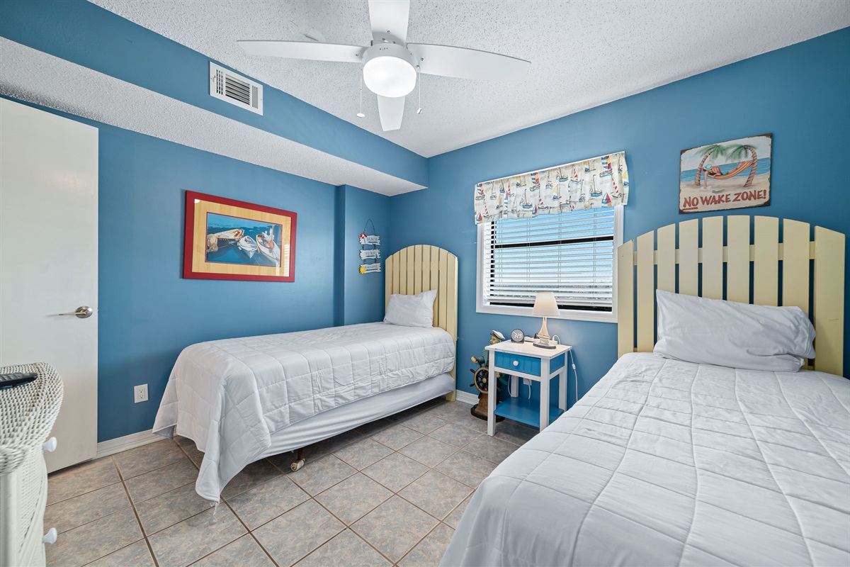 This well-appointed guest room offers two cozy twin beds, soft lighting, and a window providing natural light and a pleasant outlook.