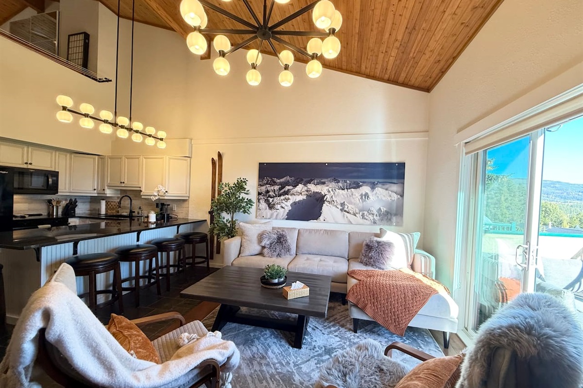 Relax on the oversized sectional framed by an aerial photograph of the Rocky Mountains — the ridge line visible from just outside that deck door.