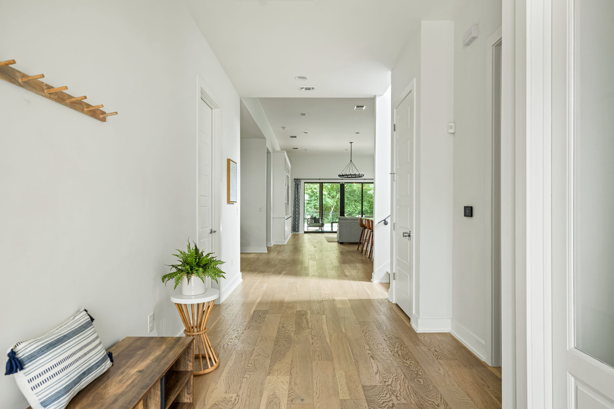 Welcoming entryway with rich hardwood floors, wall-mounted coat hooks, and stylish console table — the perfect drop zone for luggage and shoes.