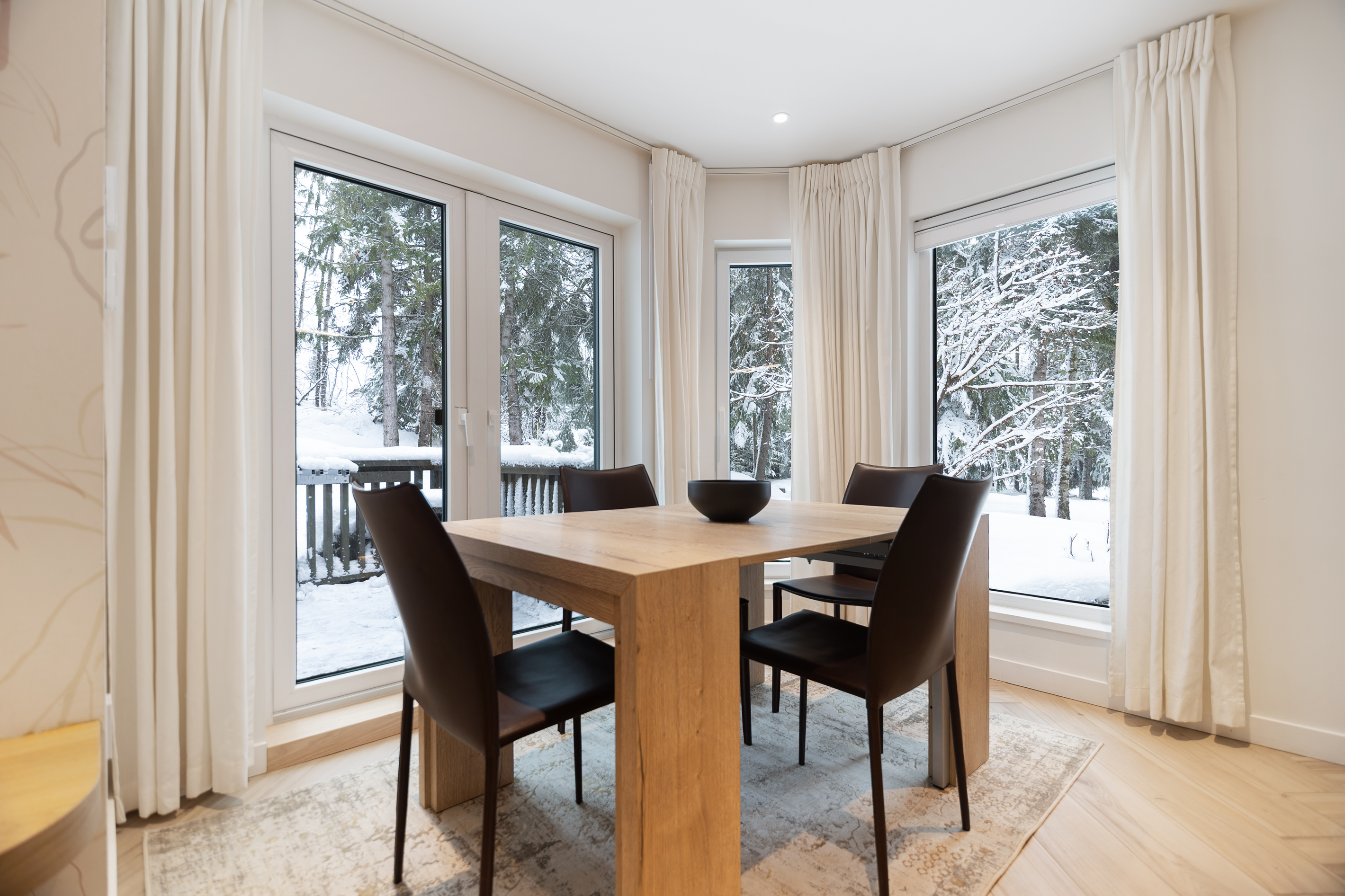 Dining table beside forest-view windows
