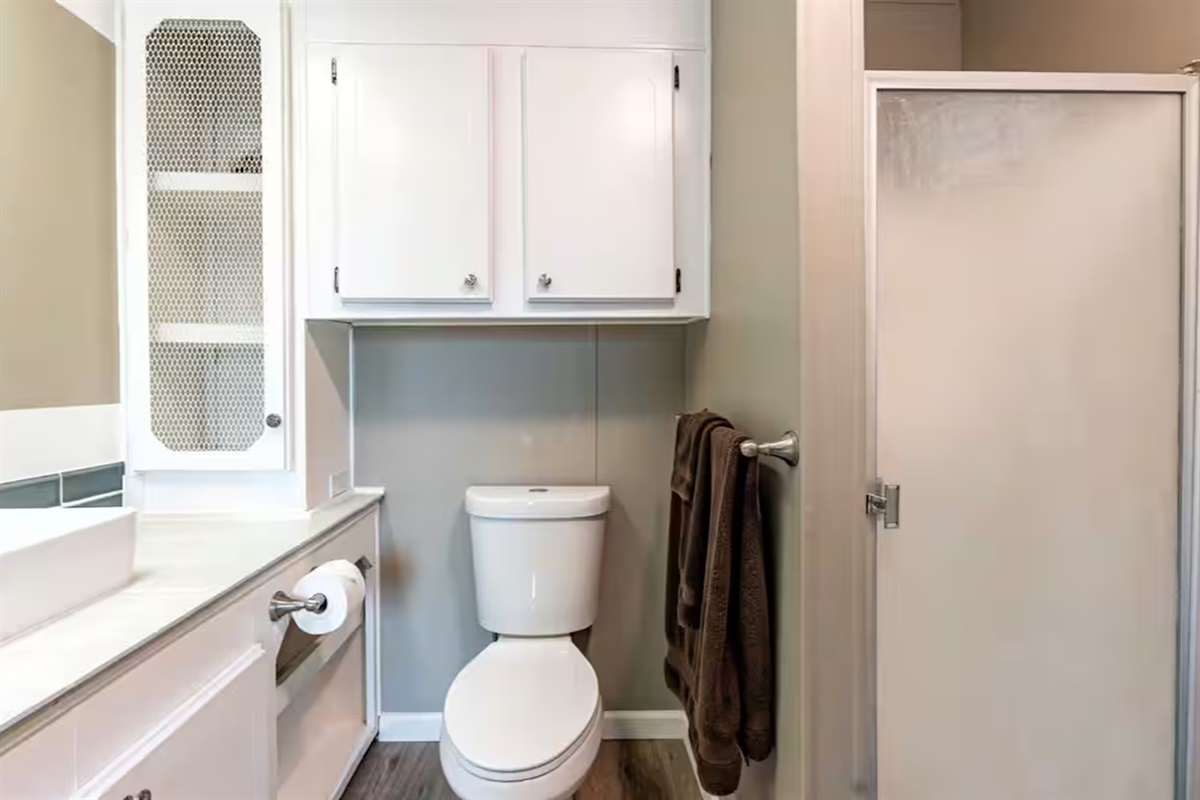 Bright, spotless bathroom with walk-in shower and ample storage.