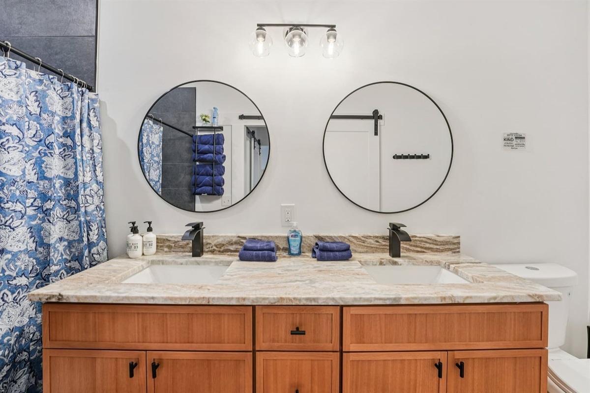 Primary bathroom has double vanity, large walk-in shower, body wash, shampoo, conditioner, plenty of towels, hair dryer, and first aid kit