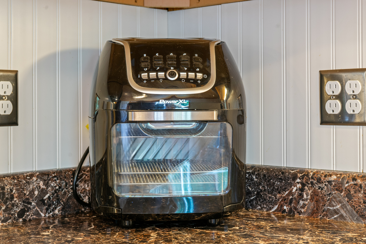 Prepare quick snacks or healthy meals using the multi-function PowerXL countertop air fryer oven. Conveniently tucked into the corner of the stone-patterned kitchen counter, this premium small appliance is perfect for easy vacation cooking.