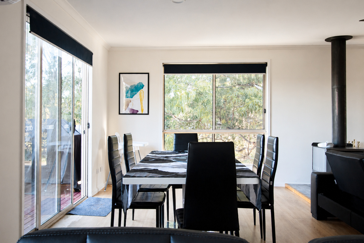 Leafy window views and deck access give the dining area at Carlenes Getaway a calm, connected feel throughout your stay.