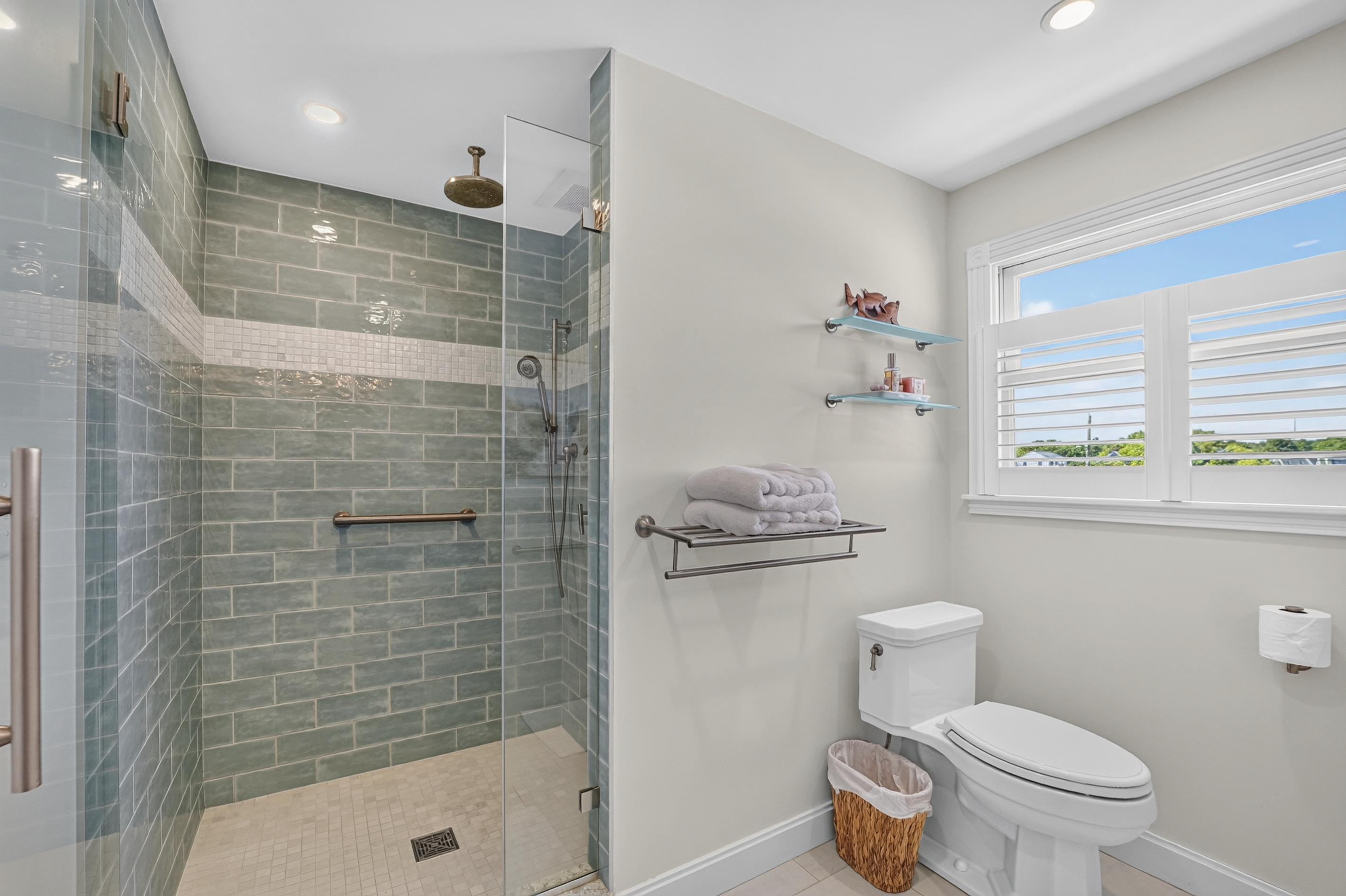 Walk-in tiled shower and bright bathroom provide a refreshing space to start or end your day.