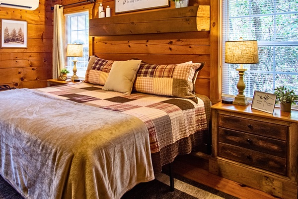 Cozy king bedroom with warm cabin charm, natural light, and peaceful views.