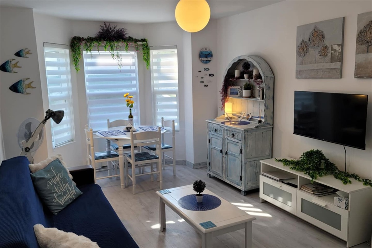 Living area with dining table for 4 guests, futon that folds in a single bed for 1 adult or 2 small children, and app TV.