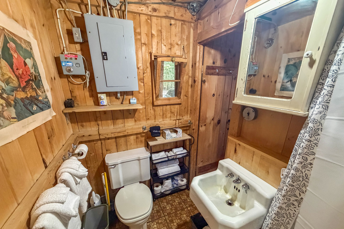 Bathroom details at Loonrise Point! Sink & plumbing run on lake-fed water (Primo dispenser in living room for drinking). Features medicine cabinet mirror, towel storage, & rustic pine charm on Beech Hill Pond in Otis, ME.