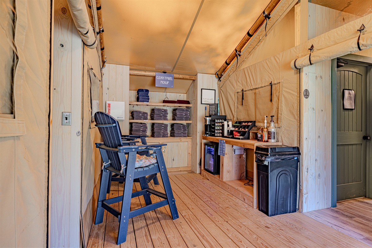A clean, bright, and welcoming gathering spot. Beyond your tent, you'll find this thoughtful space with supplies and comfortable chairs, built with warm pine paneling for a rustic feel.