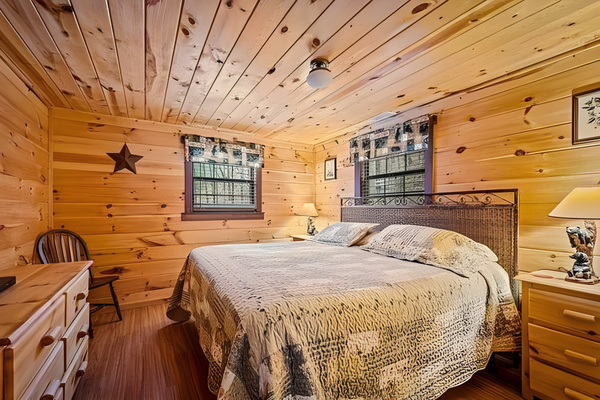 Retreat to this cozy, wood-paneled bedroom offering a comfortable king-size bed, a dedicated desk space, and a classic cabin atmosphere perfect for a restful night's sleep.  Bedroom 2 of 2 on lower level.
