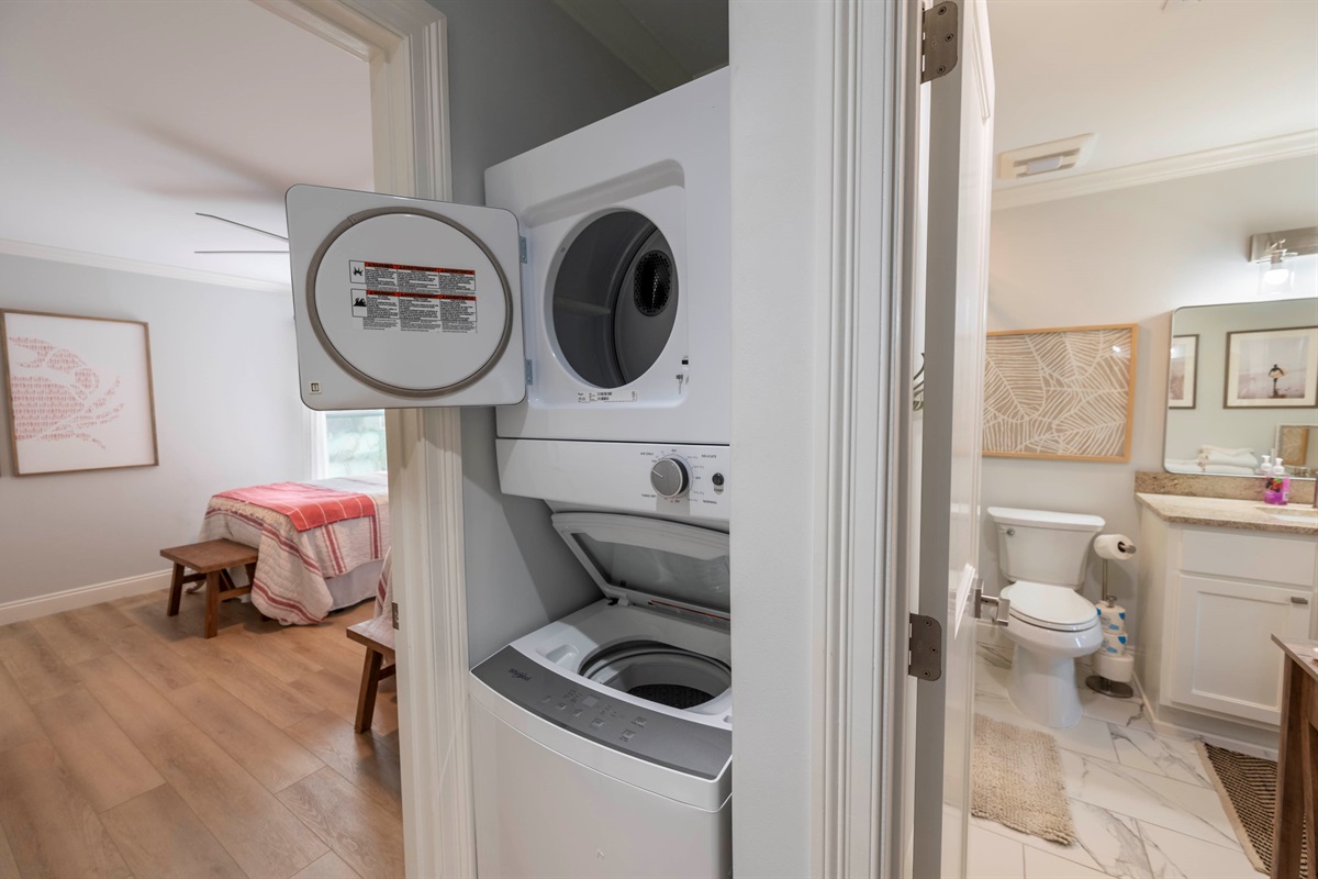 Efficient laundry nook connects cozy bedroom and stylish bathroom in modern home.