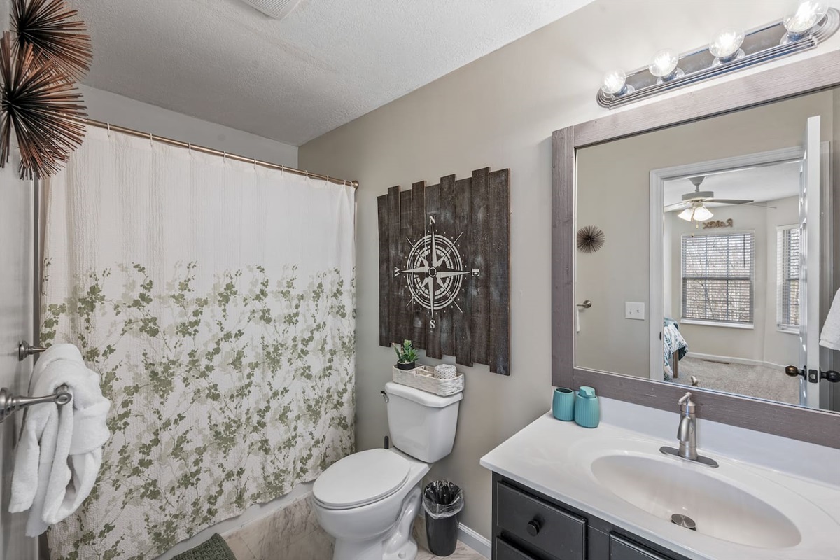 Modern bathroom with a shower/tub combo, large vanity mirror, stylish décor, and fresh towels—designed for comfort and convenience during your stay.