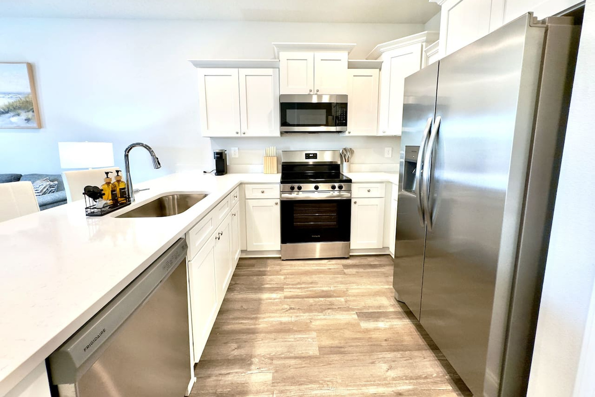 Cool countertops under your palm, the quiet hum of stainless steel appliances. Warm light overhead, wood floors underfoot. Everything crisp and clean, ready to cook, easy to move around in.