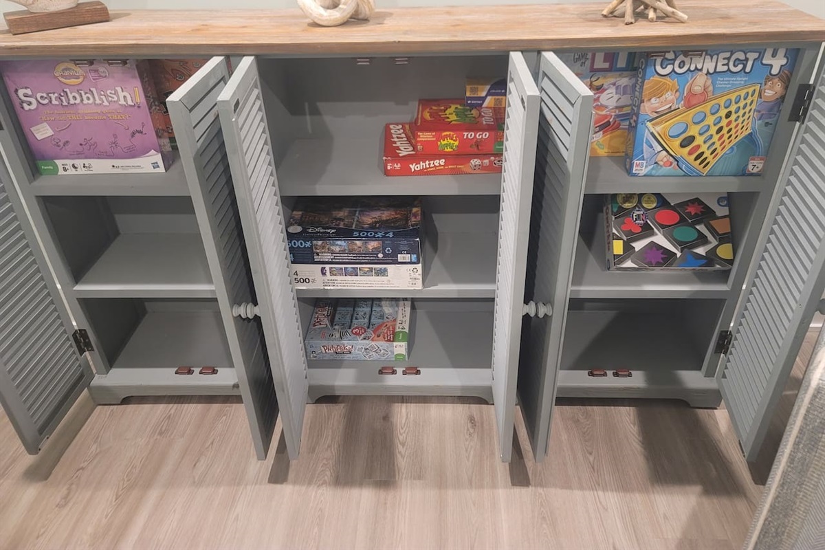 Games and puzzles in credenza cabinet for family fun.