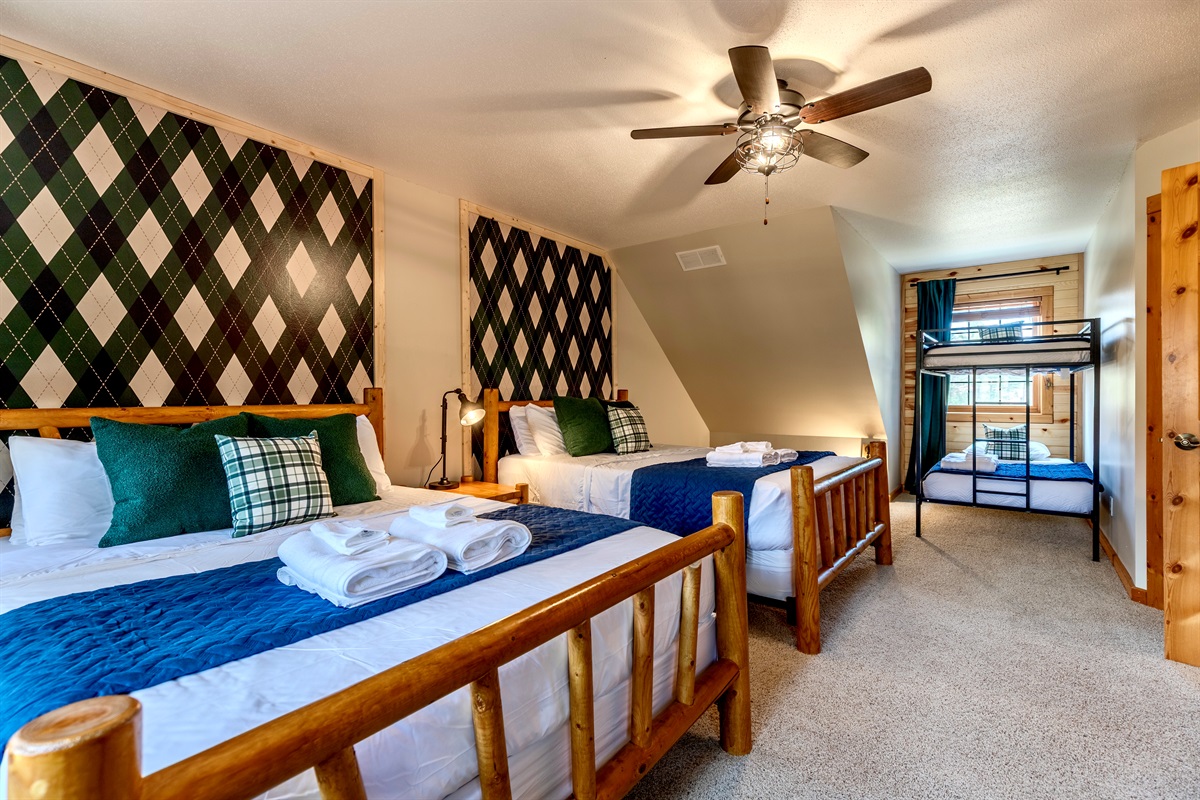 Upstairs bedroom with two queen beds and a twin over twin bed and smart TV.