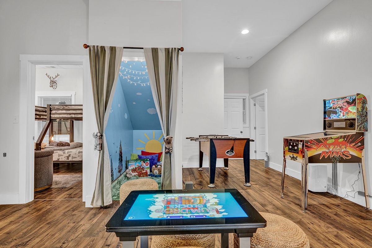 Downstairs game room with cozy large sofa, infinity game, fooseball and suffleboard tables, pinball machine and a cozy nook for the little ones.