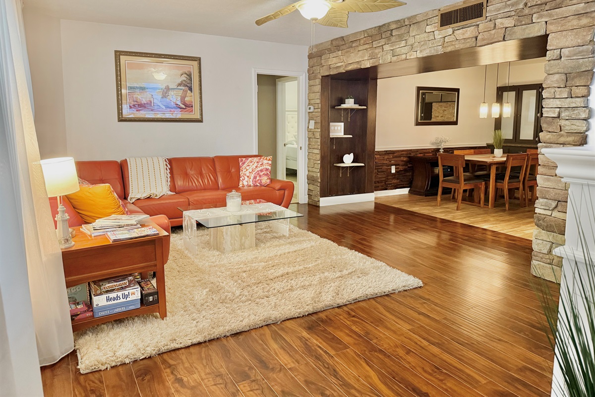 With bold burnt-orange seating, glass-top coffee table, and a shag rug underfoot, this space blends retro flair with modern comfort.